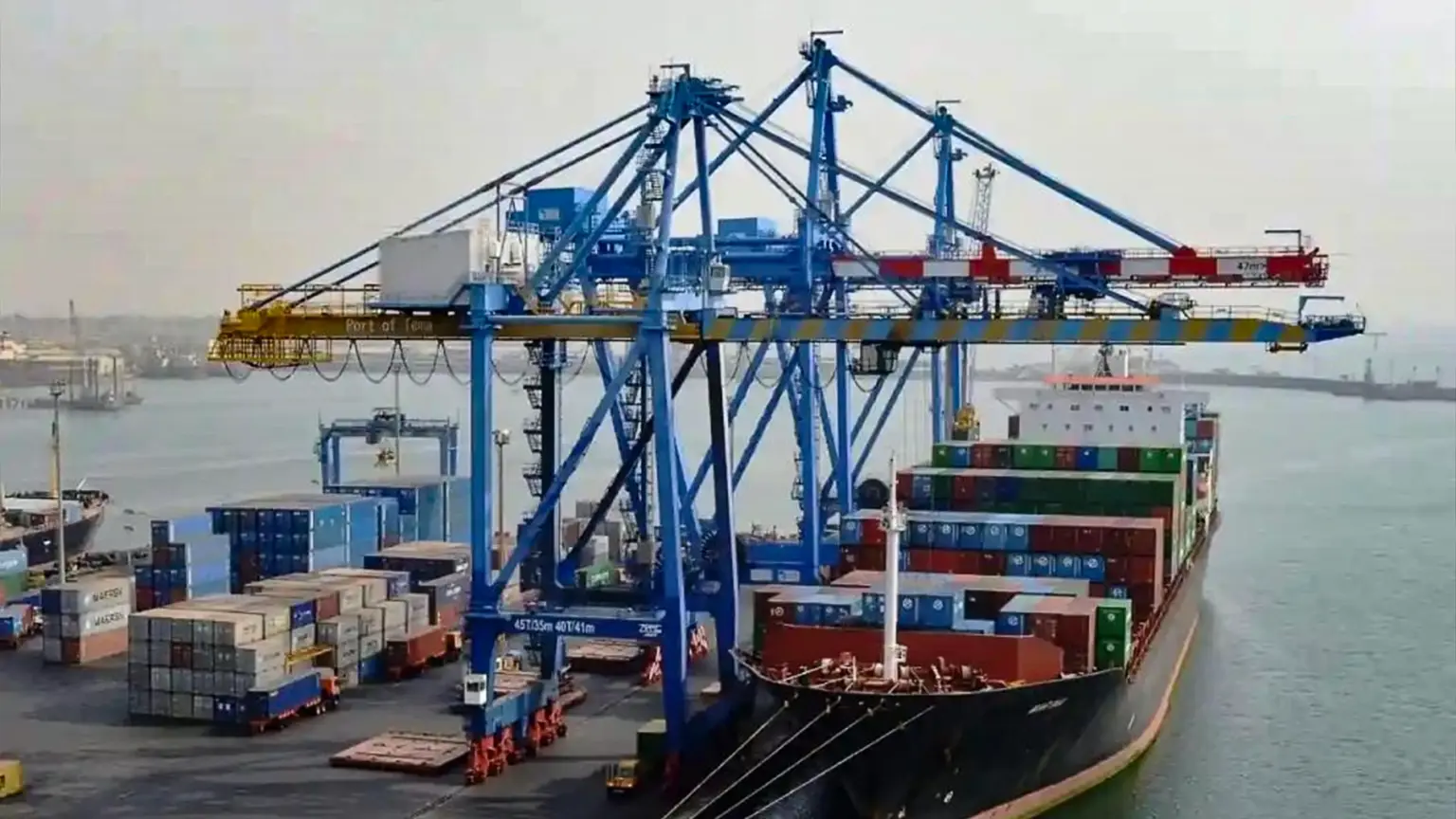 Cargo ship being loaded with shipping containers by gantry cranes at a port